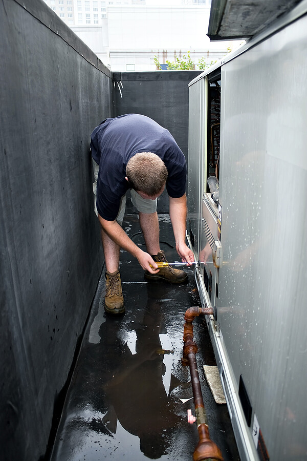 Mast tech using screwdriver to fix commercial HVAC issue in Holland