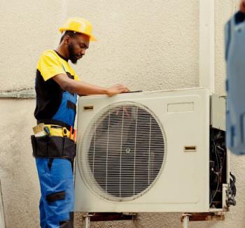 HVAC technician in a hard hat working on a ductless mini split in Grand Rapids